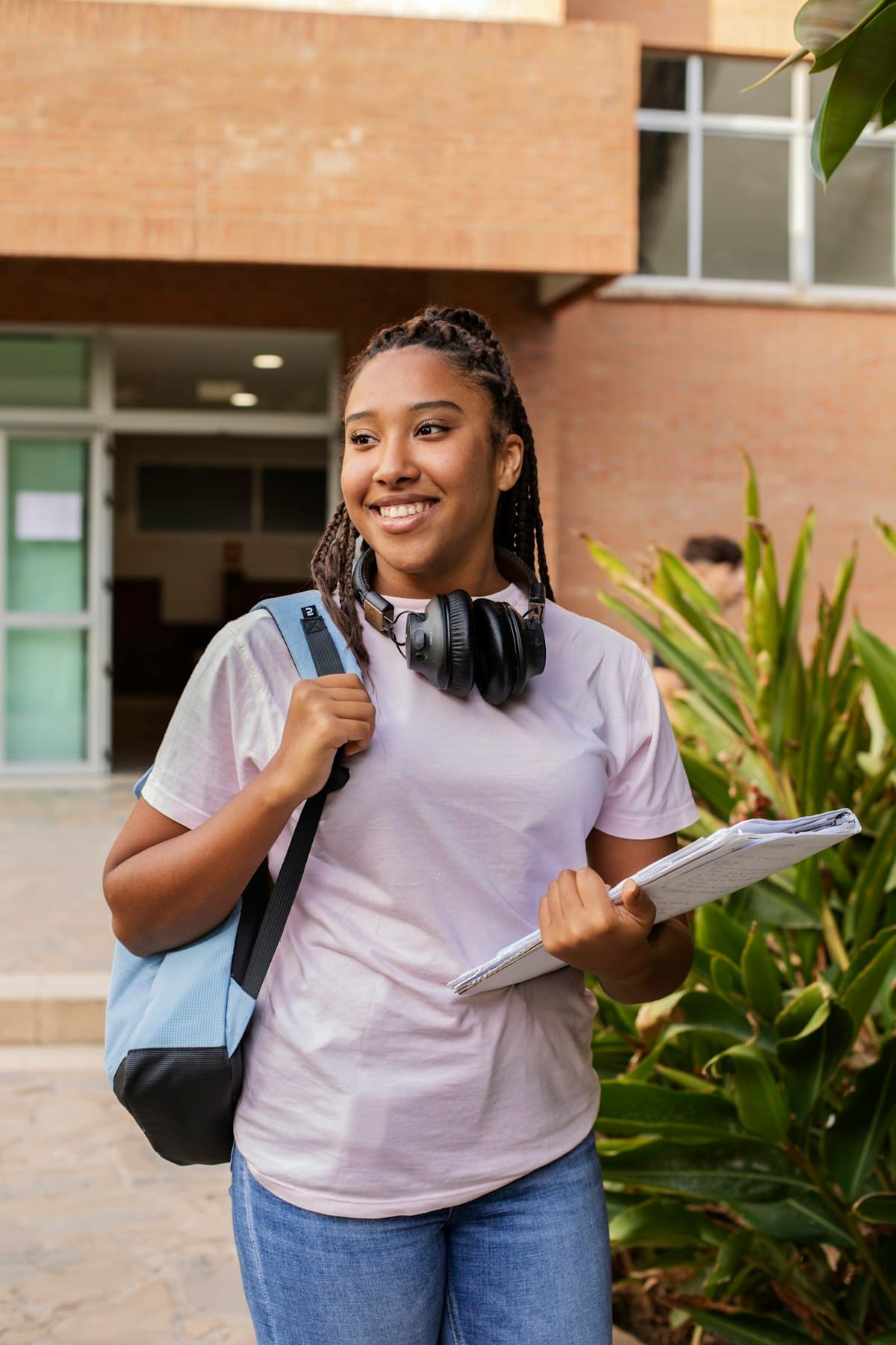 A smiling student with a backpack walking outside a campus building
