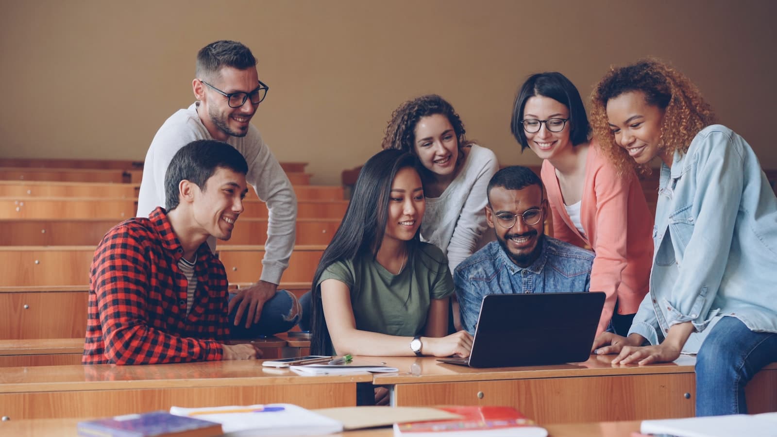 Students from different countries working together around a laptop